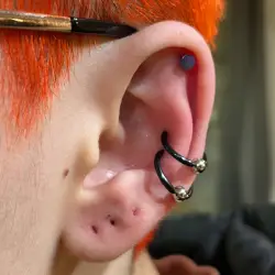 Cette fille au cheveux court orange est fière de montrer ses 3 nouveaux perçages de cartilage dont deux conch piercings et un Helix piercing car elle a eu le meilleur prix piercing oreille Montréal.