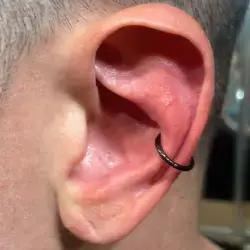 Conch Piercing de 14 gauge avec une anneau pleine noir en Titanium dans l'oreille gauche d'un homme aux cheveux rasés.