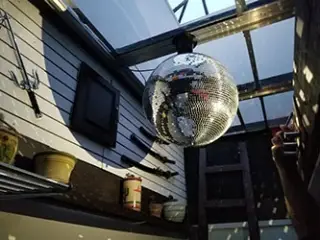 Vue d'une énorme boule disco dans un puit de lumière d'un Studio de Body Piercing du centre-ville de Montréal offrant le service de perçage des oreilles.